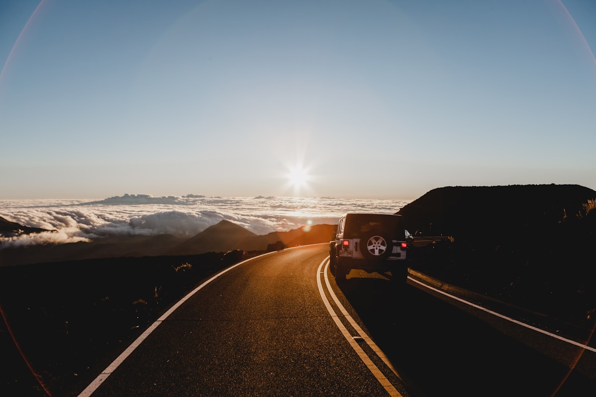 An SUV on a scenic mountain road at sunrise