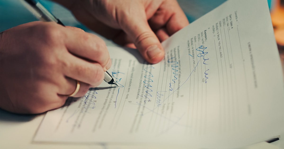 Hands signing loan documents at a desk