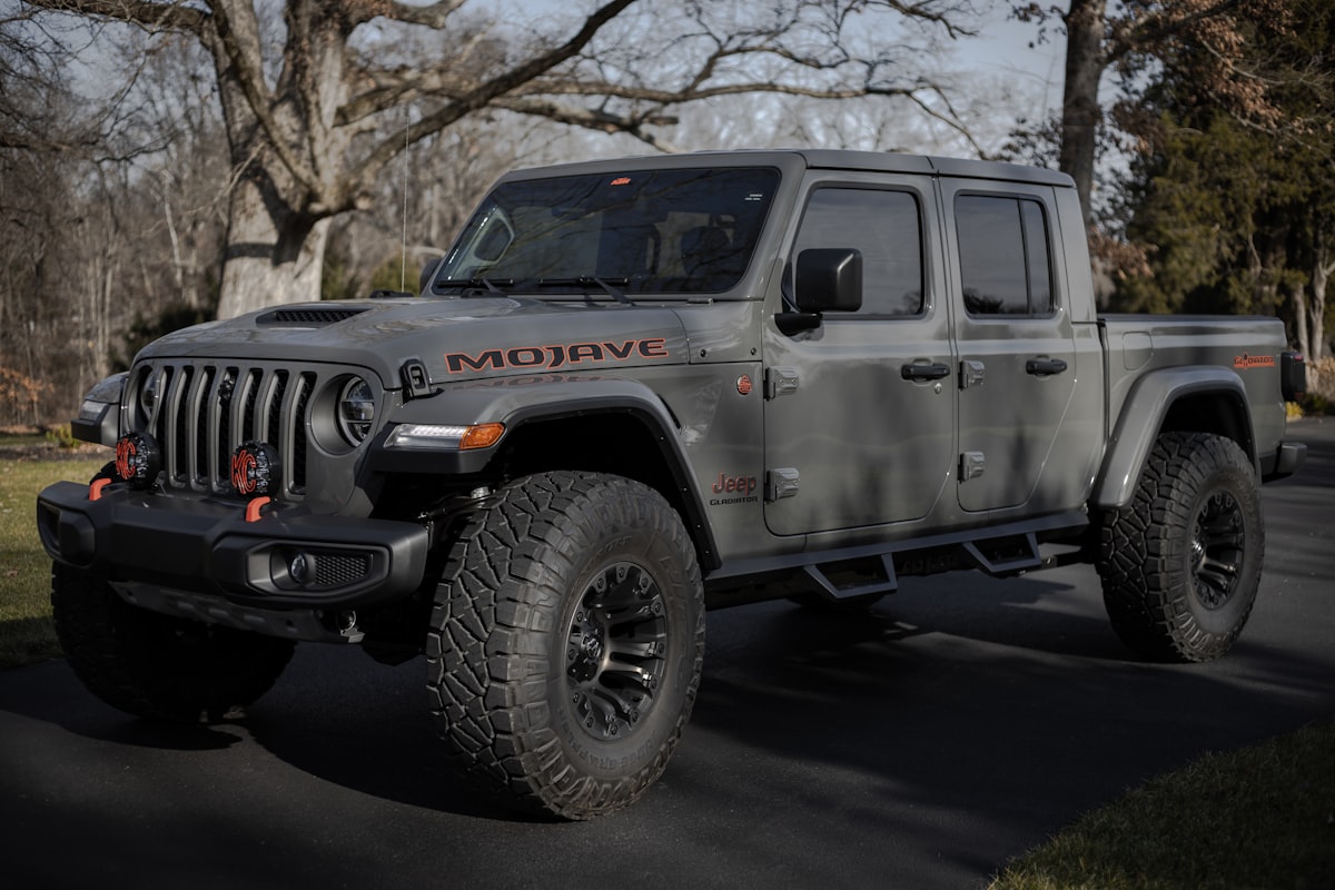 Gray Jeep Gladiator pickup parked on a tree-lined driveway