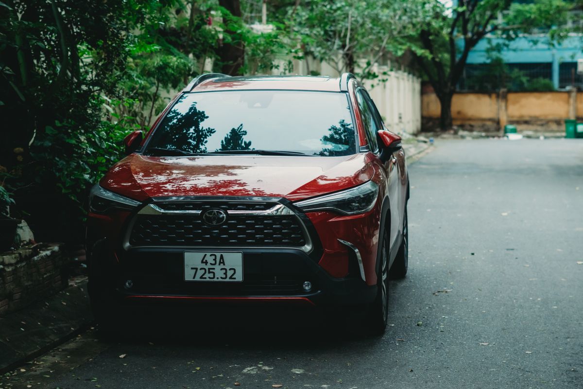 Red Toyota Corolla Cross parked on a tree-lined street
